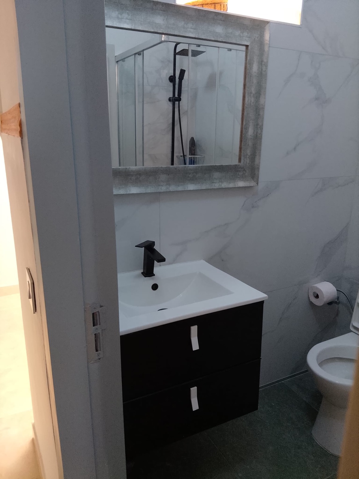 Baño reformado con lavabo suspendido, mueble y alicatado de mármol